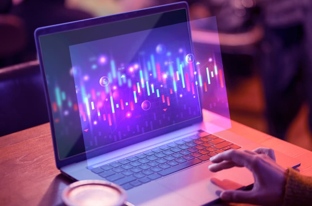 Close-up of hands on a laptop with vibrant trading chart holograms