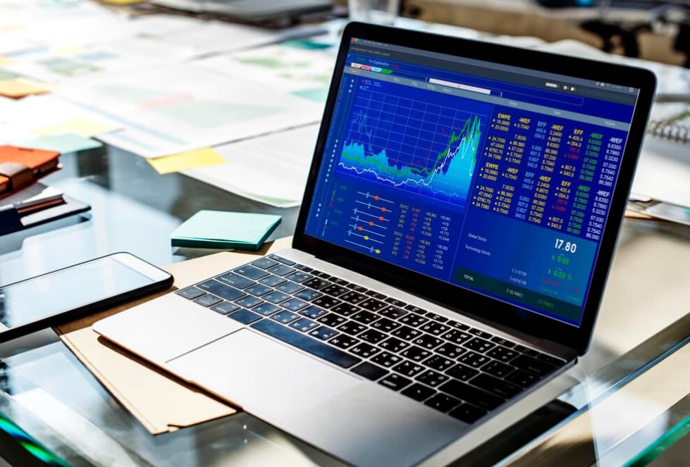 Laptop on a desk displaying colorful stock market graphs